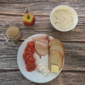 Zdjęcie przedstawia Dietę podstawową: Kawa zbożowa z mlekiem Owsianka budyniowa z bananem i jabłkiem z posypką chia Chleb mieszany pszenno-żytni Masło extra Szynka Piastowska Pomidor Jabłko Twarożek